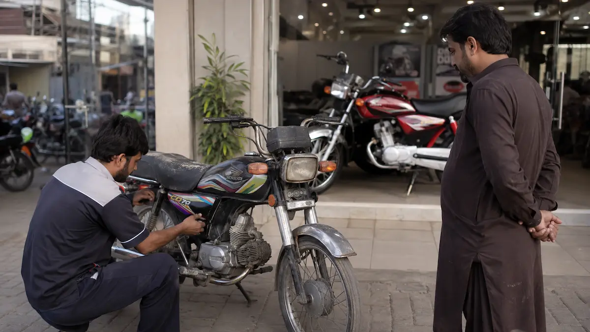 Honda CD70 owner trading an old motorcycle for an upgraded new bike at a Pakistan dealership